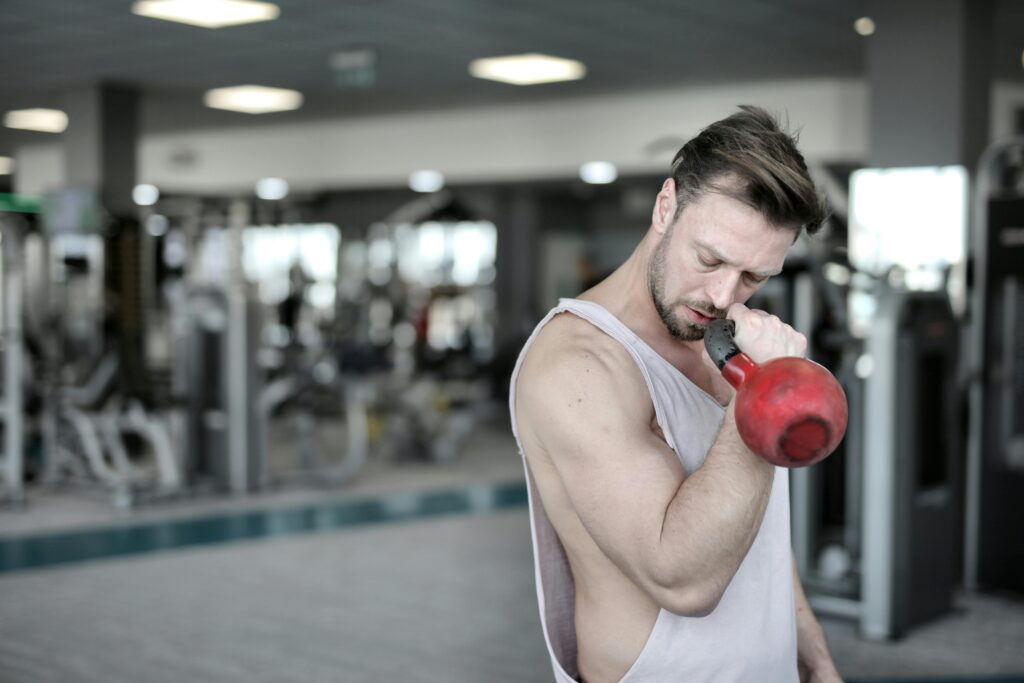 An athletic man working out with a kettlebell in a gym setting, emphasizing strength training.